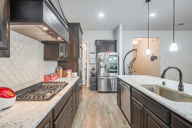 kitchen featuring sink, appliances with stainless steel finishes, hanging light fixtures, dark brown cabinets, and custom exhaust hood