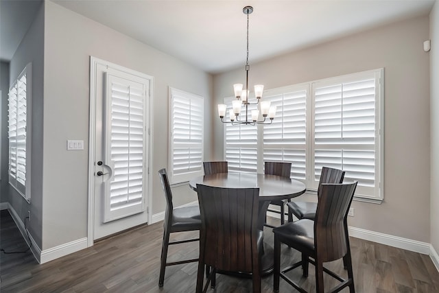 dining area with dark hardwood / wood-style flooring and an inviting chandelier