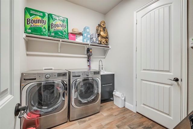 washroom featuring sink, light hardwood / wood-style flooring, and washing machine and clothes dryer