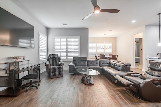 living room with wood-type flooring and ceiling fan with notable chandelier