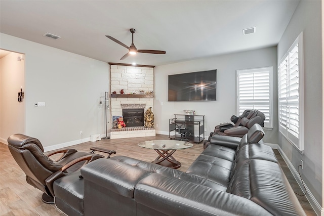 living room featuring a fireplace, light hardwood / wood-style floors, and ceiling fan