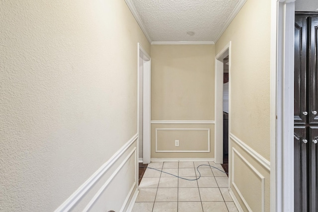 corridor with crown molding, light tile patterned floors, and a textured ceiling