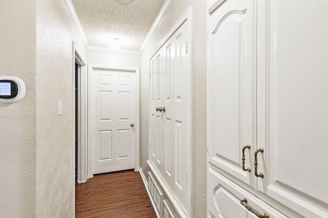 hallway with ornamental molding, dark hardwood / wood-style floors, and a textured ceiling