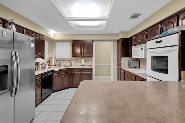 kitchen with sink, light tile patterned floors, backsplash, and white appliances