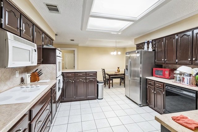 kitchen with dark brown cabinets, pendant lighting, white appliances, and decorative backsplash