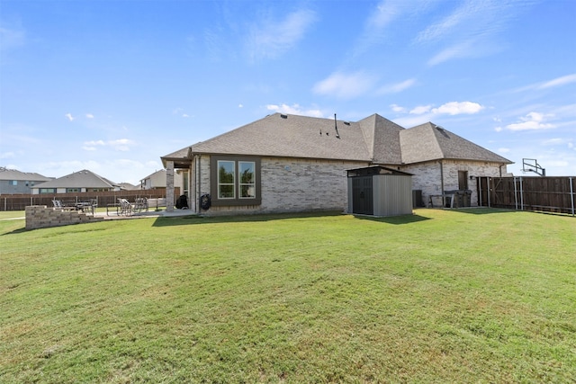 rear view of property with a patio, a lawn, and a storage unit