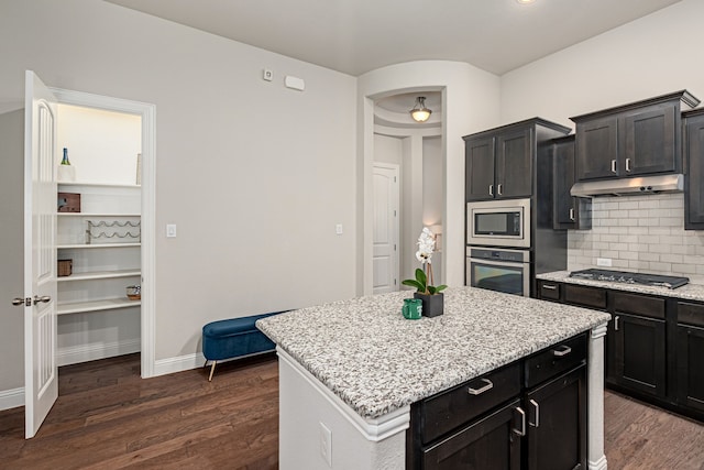 kitchen with a kitchen island, appliances with stainless steel finishes, dark hardwood / wood-style flooring, and decorative backsplash