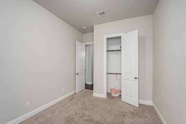 unfurnished bedroom with light colored carpet and a closet