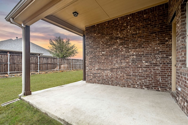 patio terrace at dusk featuring a yard