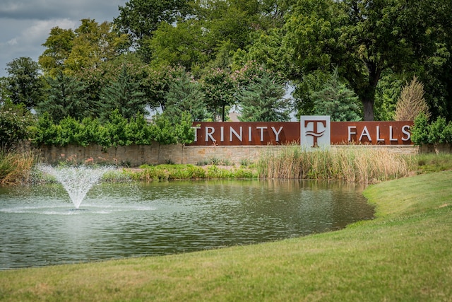 community / neighborhood sign featuring a yard and a water view