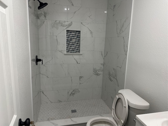 bathroom with tiled shower and toilet