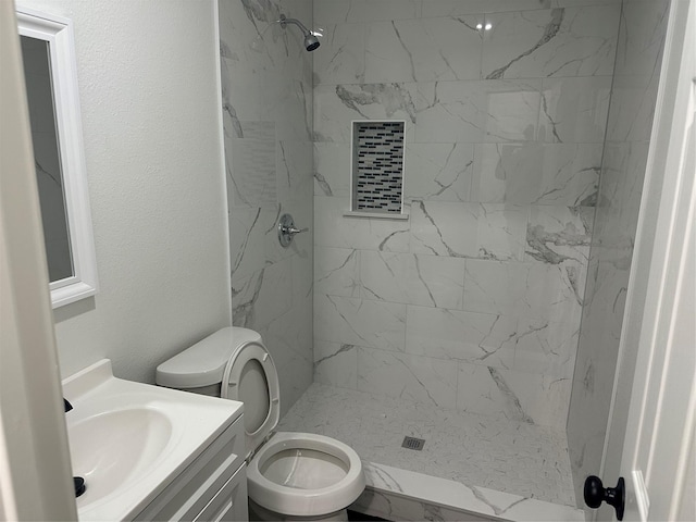 bathroom with tiled shower, vanity, and toilet