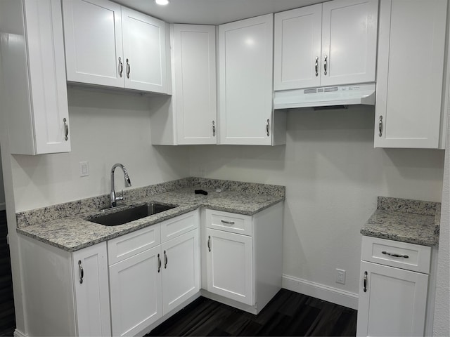 kitchen featuring white cabinetry, dark hardwood / wood-style flooring, light stone countertops, and sink