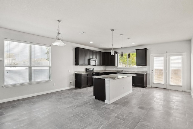 kitchen featuring pendant lighting, light stone counters, stainless steel electric stove, and a center island