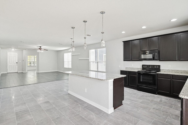 kitchen with light stone counters, hanging light fixtures, black appliances, and a kitchen island