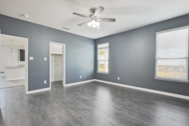 unfurnished bedroom with ceiling fan, dark hardwood / wood-style floors, a closet, and a spacious closet