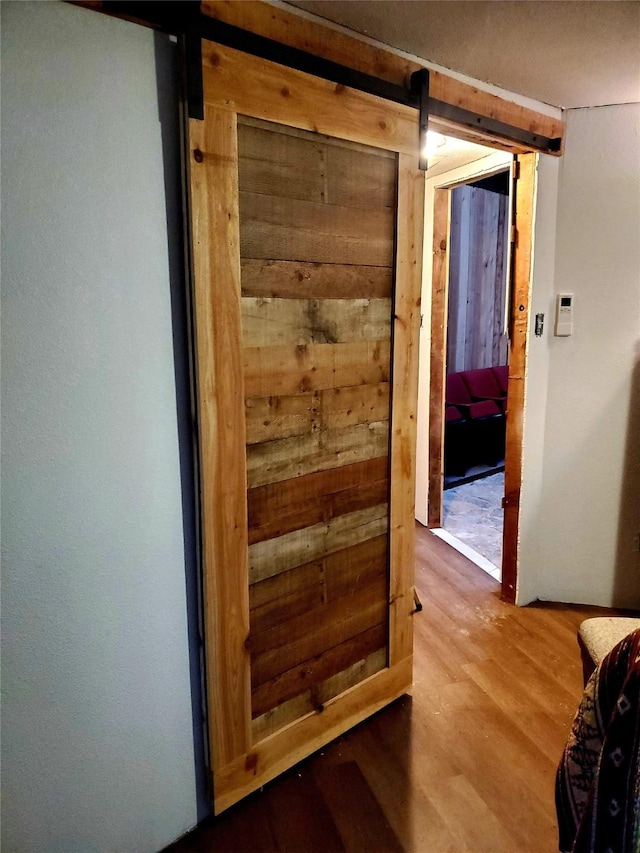 hall featuring wood-type flooring, a barn door, and wood walls