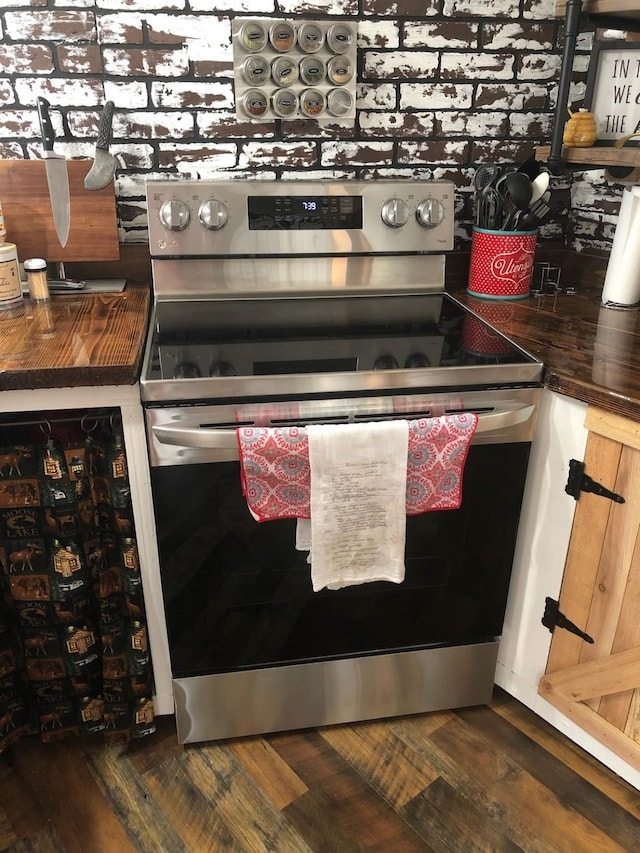 room details with dark hardwood / wood-style floors and stainless steel range with electric cooktop