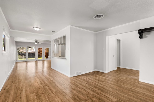 unfurnished living room featuring crown molding, ceiling fan, wood-type flooring, and a textured ceiling