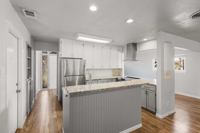 kitchen with light stone counters, extractor fan, hardwood / wood-style floors, and stainless steel appliances