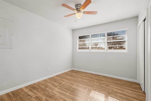 spare room with ceiling fan, electric panel, and light hardwood / wood-style floors