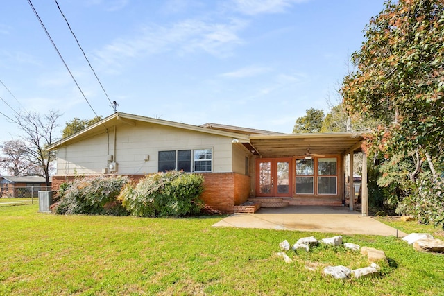 rear view of property featuring a yard, central AC, and a patio area