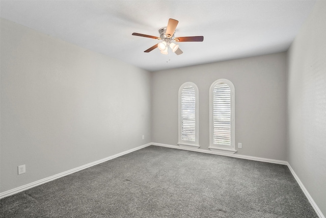 empty room featuring ceiling fan and dark colored carpet