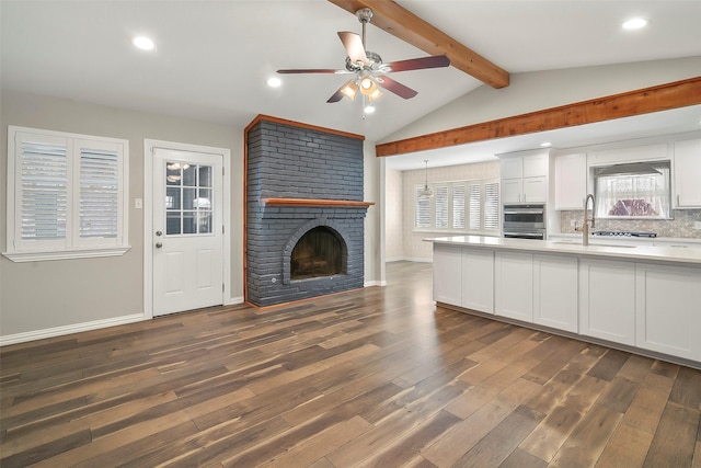 kitchen with white cabinetry, tasteful backsplash, lofted ceiling with beams, and stainless steel oven