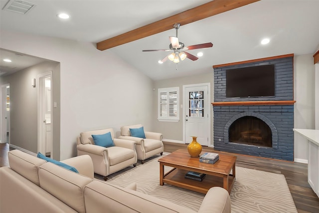 living room with hardwood / wood-style flooring, ceiling fan, lofted ceiling with beams, and a brick fireplace