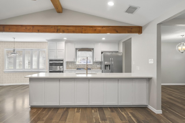 kitchen with appliances with stainless steel finishes, sink, vaulted ceiling with beams, white cabinets, and hanging light fixtures