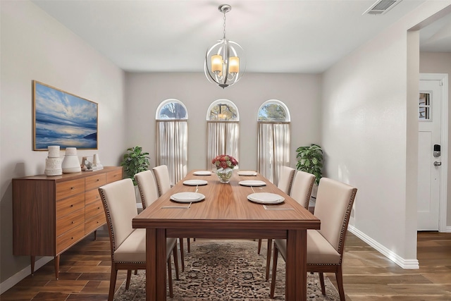 dining space featuring dark wood-type flooring and an inviting chandelier