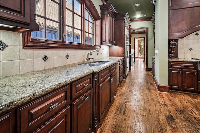 kitchen featuring sink, dark wood-type flooring, tasteful backsplash, light stone countertops, and ornamental molding