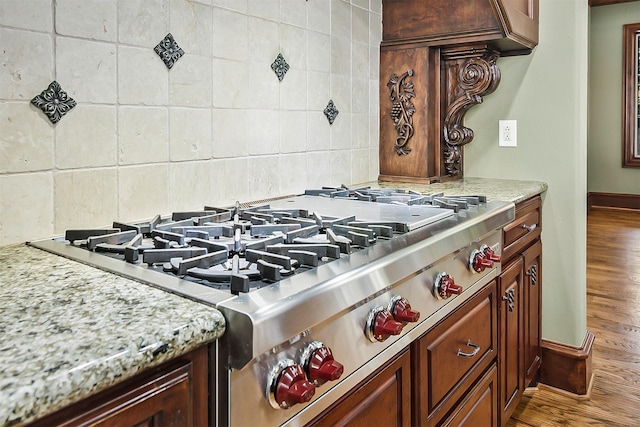 kitchen featuring hardwood / wood-style flooring, light stone countertops, and backsplash