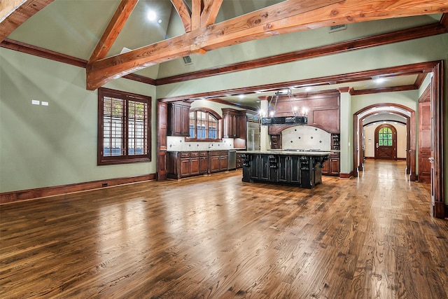 kitchen with backsplash, a kitchen island, dark hardwood / wood-style floors, a kitchen bar, and beamed ceiling