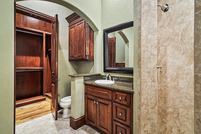 bathroom with vanity, toilet, and tiled shower