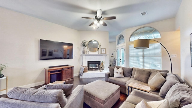 living room featuring a brick fireplace, dark wood-type flooring, and ceiling fan