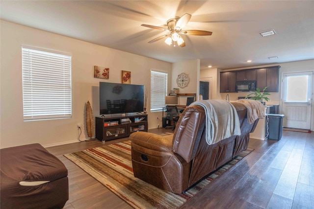 living room featuring ceiling fan and dark hardwood / wood-style flooring