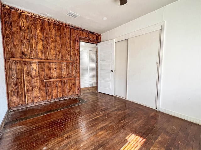 unfurnished bedroom featuring dark wood-type flooring, a closet, and ceiling fan