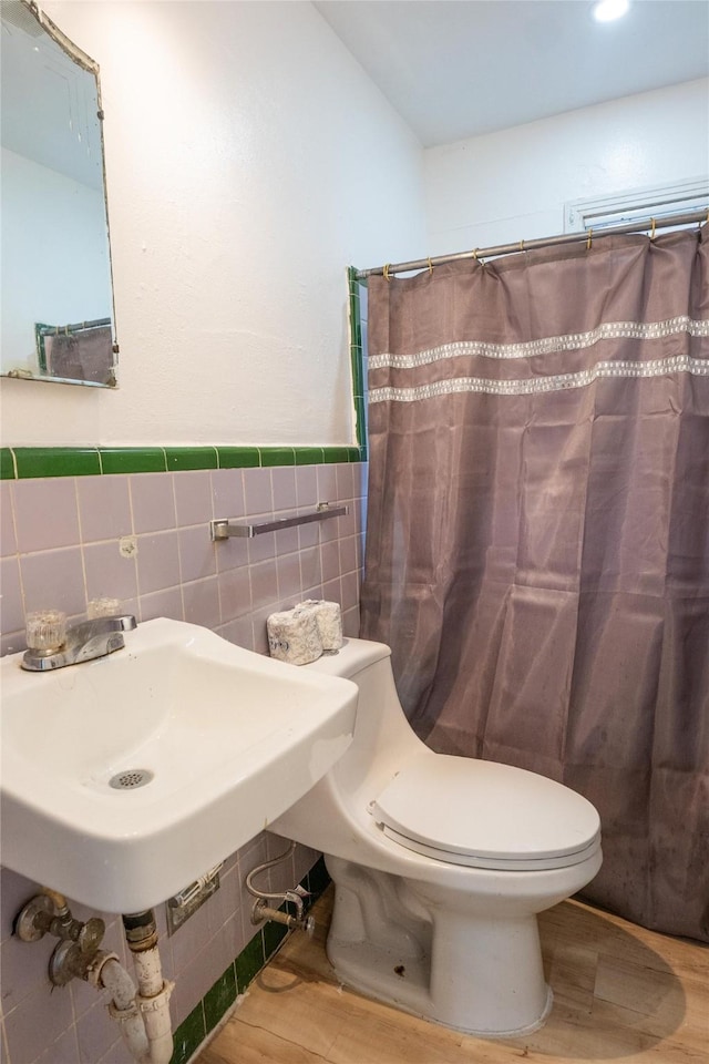 bathroom featuring wood-type flooring, sink, tile walls, and toilet