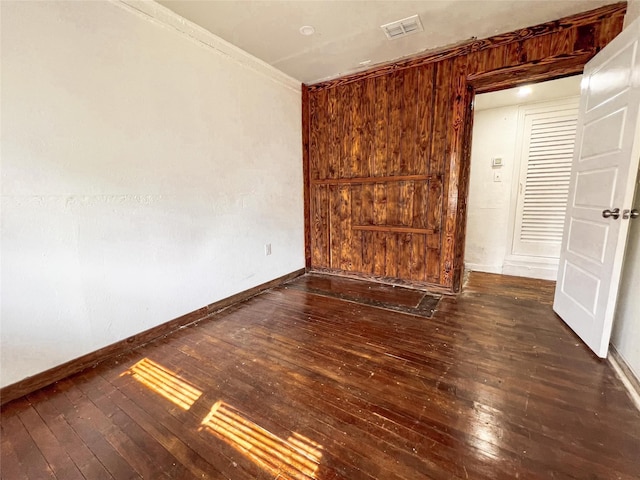 empty room with ornamental molding and dark hardwood / wood-style floors