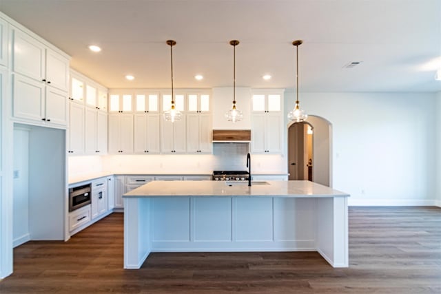 kitchen with stainless steel microwave, white cabinets, and a center island with sink