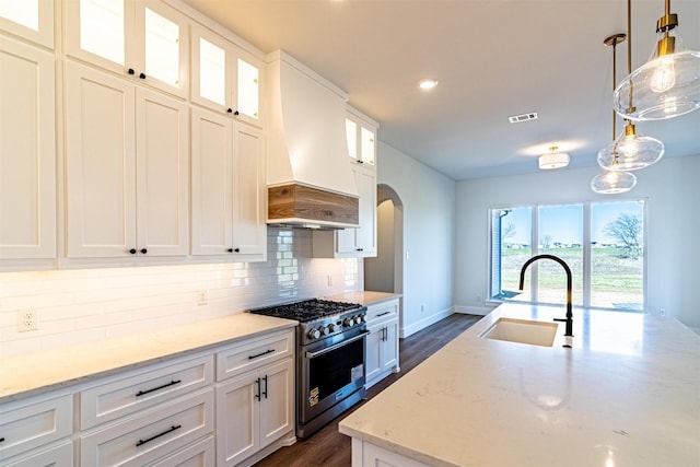 kitchen featuring premium range hood, high end range, sink, and white cabinets