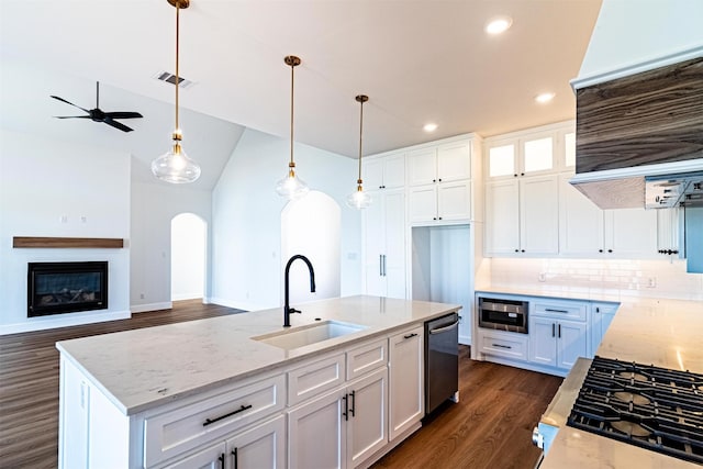 kitchen featuring light stone countertops, sink, a center island with sink, and white cabinets