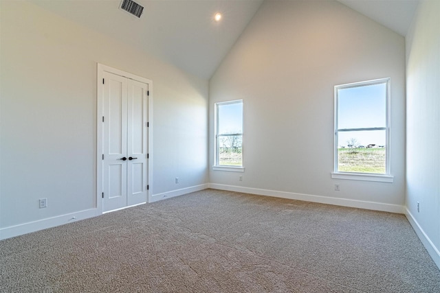 empty room with carpet floors and high vaulted ceiling