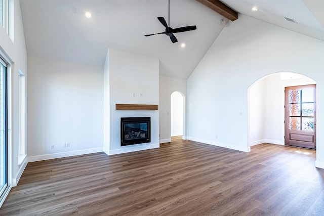 unfurnished living room featuring dark hardwood / wood-style floors, beam ceiling, and high vaulted ceiling