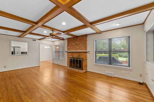 unfurnished living room featuring ceiling fan, beam ceiling, coffered ceiling, light hardwood / wood-style floors, and a brick fireplace