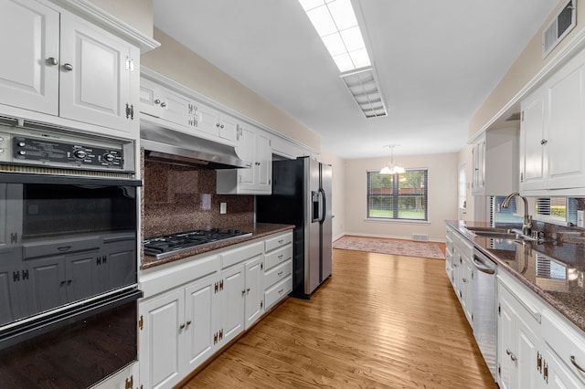 kitchen featuring sink, tasteful backsplash, dark stone countertops, stainless steel appliances, and white cabinets