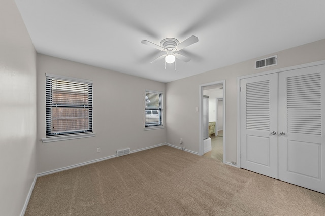 unfurnished bedroom with light colored carpet, ceiling fan, and a closet