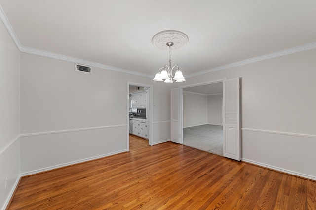 unfurnished dining area featuring ornamental molding, hardwood / wood-style floors, and an inviting chandelier