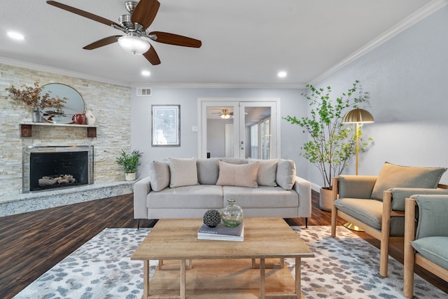 living room with hardwood / wood-style floors, a stone fireplace, and ornamental molding